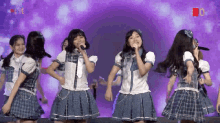 a group of girls are singing into microphones on a stage with a purple background that says live
