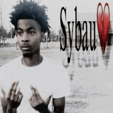 a man in a white shirt is standing in front of a broken heart and giving the middle finger .