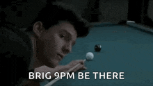 a man is playing pool and the words `` brig 9 pm be there '' are written on the screen .