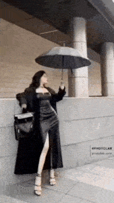 a woman in a long black dress is holding an umbrella .