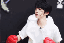 a man wearing red boxing gloves has a tattoo on his face