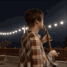a man in a plaid shirt is holding a guitar