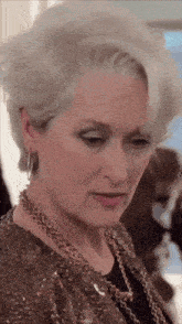 a woman with gray hair and a gold necklace