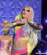 a woman in a colorful crop top and shorts is dancing on a stage ..