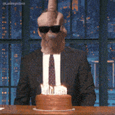 a man in a suit and tie is blowing out candles on a cake
