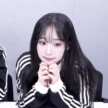 a girl with long black hair wearing a black and white striped sweater