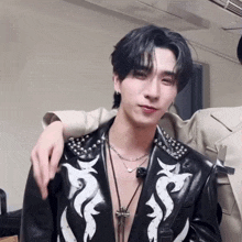 a man in a black leather jacket has a cross necklace on his neck