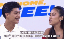a man and a woman are smiling and talking in front of a sign that says home