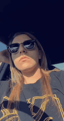 a man with long hair is wearing sunglasses and a black shirt .