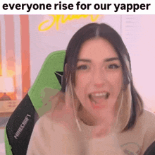 a woman is sitting in a green chair with her mouth open and a caption that says everyone rise for our yapper .