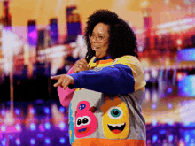 a woman wearing a colorful sweater with monster faces on it