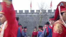 a group of men in red robes and hats are standing in front of a brick wall