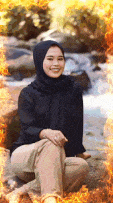 a woman wearing a black hijab is smiling in front of a fire frame