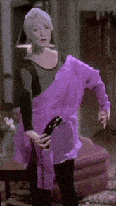 a woman in a purple dress is holding a black object