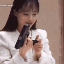 a woman in a white shirt is holding a gun in her mouth .