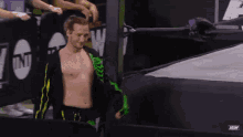 a shirtless wrestler in a green skeleton outfit is walking out of the ring .