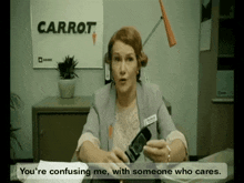 a woman sits at a desk in front of a carrot poster