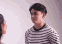 a man in a striped shirt is standing next to a woman and they are looking at each other .