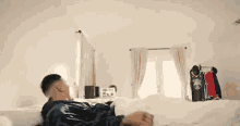 a man is laying on a bed in a bedroom with a basketball jersey on the wall .