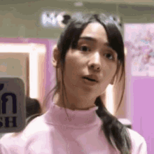 a close up of a woman wearing a pink turtleneck sweater making a funny face .