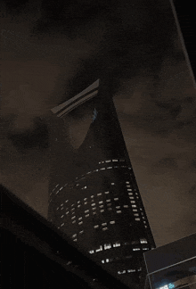 a very tall building is lit up at night with a dark sky