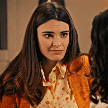 a woman wearing an orange cardigan and a polka dot shirt