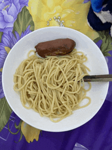 a plate of spaghetti and a sausage with a fork