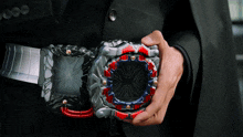 a man in a suit is holding a black and red item