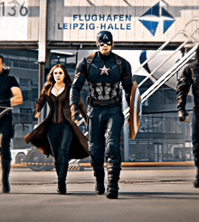 captain america and scarlet witch are walking in front of a building that says flughafen leipzig halle