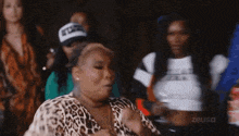 a woman in a leopard print shirt is dancing in a room with other women .