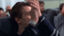 a man is sitting on an airplane with his hands on his face .
