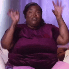 a woman is sitting on a couch with her arms in the air .