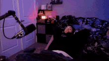 a person is laying on a bed in front of a microphone in a dark room