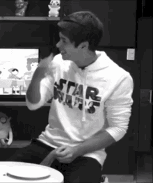 a man wearing a white star wars hoodie is sitting at a table