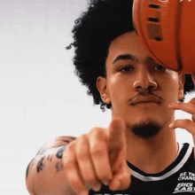 a basketball player is pointing at the camera and his shirt says be the change big east