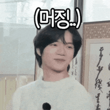 a young man in a white sweater is standing in front of a framed picture with chinese writing on it .