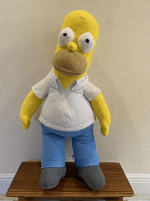 a homer simpson stuffed animal is sitting on a wooden table