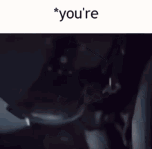 a man in a suit is sitting in a dark room with the words you 're above him