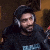 a man with a beard wearing headphones is sitting in front of a microphone .