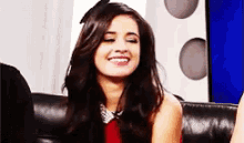 a woman is smiling while sitting on a couch with her eyes closed .