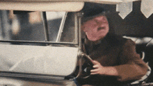 a man wearing a helmet is sitting in a car looking out the window