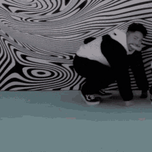 a man is kneeling down in front of an optical illusion wall .