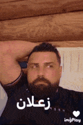 a man with a beard is laying on a bed with his hand on his head and a heart next to him