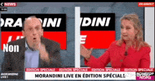 a man and a woman are sitting in front of a news screen .