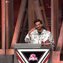 a man stands behind a podium with a bottle of charged soda on it