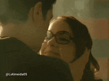 a woman wearing glasses is being kissed by a man with the name lialmeida05 on the bottom right