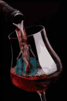 a bottle of wine is pouring into a glass with a belly dancer in it