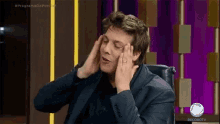 a man in a suit is sitting in a chair with his hands on his ears .