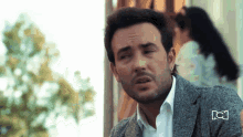 a man with a beard is wearing a grey jacket