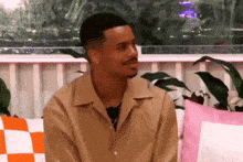 a man in a tan shirt is sitting on a couch looking at something